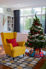 Big yellow chair in living room with Christmas tree and gift presents for Christmas Day festival coming soon as background