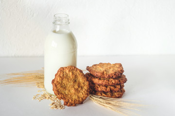 Oatmeal cookies and a glass bottle with milk on a light background, healthy nutrition. Breakfast or evening snack