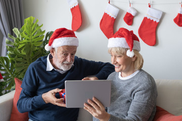 senior elderly caucasian old man and woman, using conference on tablet with family together in living room that decorated for christmas festival day in the morning, retirement concept