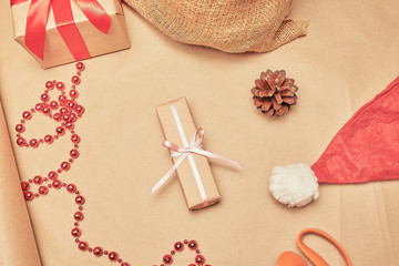 Christmas composition. Gift box with a light pink ribbon and christmas decorations on a brown paper background.