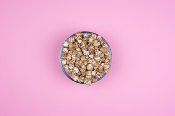 Caramel sweet popcorn bowl isolated on pink background top view. Top view, copy space.