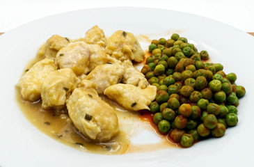 Close-up Chicken curry served with green peas in a white dish, wooden table.