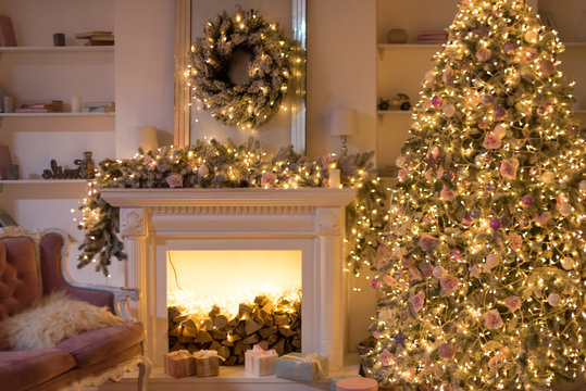 Warm cozy evening, Christmas eve, Christmas room with fireplace interior design, Xmas tree decorated by lights, gifts toys, garland lighting fireplace. Happy Winter Holidays, holiday living room.