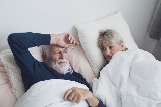 elderly couple caucasian senior man talking or discussion together and try to sleep in white blanket in bedroom, retirement love lifestyle concept