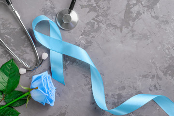Blue ribbon, stethoscope and rose on concrete background, prostate cancer awareness concept.