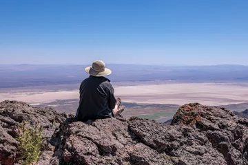 Fotobehang Young woman in a stray hat sitting on a cliff overlooking Alvord Desert. Steens Mountains, south Oregon © Dmitry