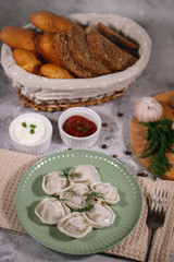 Ravioli on a plate with dill, served with sauce and ketchup. Boiled dumplings on a dish. Tasty dinner. Food. Close-up.