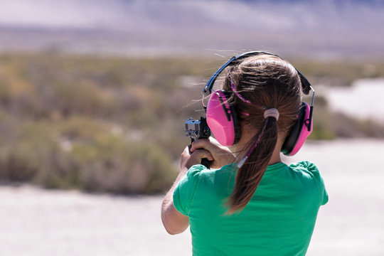 Little girl practicing target shooting with 22LR caliber pistol in desert place of south Oregon