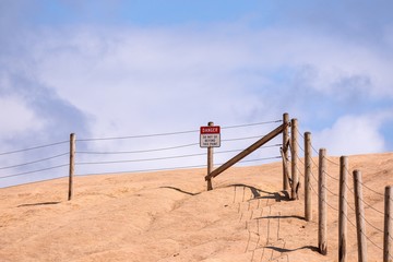 Fototapeta na wymiar Posted sign on a edge of a cliff of Cape Kiwanda read 