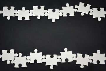 silver metal puzzle pieces arranged as a frame on black color background with copy space, business partnership concept