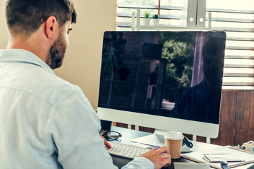 Office worker doing his job sitting at his working table with a computer