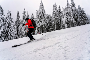 Fototapeta na wymiar Female skier dressed in red jacket on ski slope.