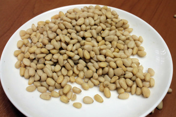 Peeled pine nuts on a white plate.