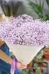 Lilac gypsophila. Beautiful bouquet of mixed flowers in womans hands. the work of the florist at a flower shop. Fresh cut flower.