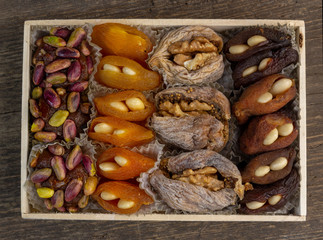 Sweet natural eastern delight with dried apricots, figs, walnuts, pistachios and almonds on a rustic wooden background with copy space.