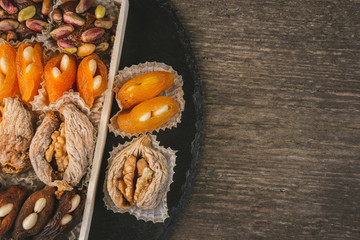 Sweet natural eastern delight with dried apricots, figs, walnuts, pistachios and almonds on a rustic wooden background with copy space.