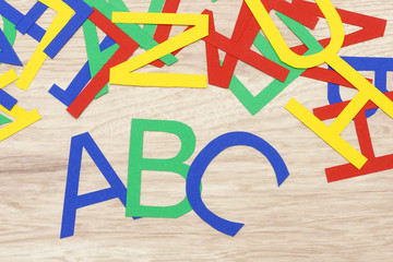 colorful jumbled letters, made of paper,  lying on wood