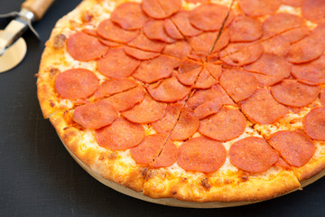 Tasty Pepperoni pizza over black background, side view. Close-up.