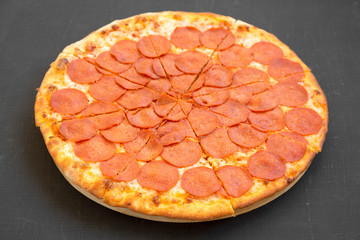 Tasty Pepperoni pizza over black surface, low angle view. Close-up.
