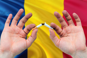 Chad quit smoking cigarettes concept. Adult man hands breaking cigarette. National health theme and country flag background.