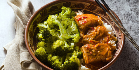 banner of Thai salmon dish in coconut sauce with fresh broccoli and rice in a clay bowl with chopsticks . healthy food with vitamin B5...