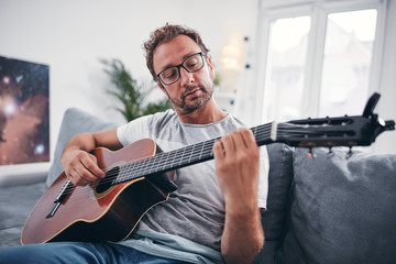 Man playing acoustic guitar in the living room.