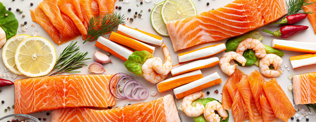 banner of fresh seafood on a table with spices, vegetables and olive oil: fresh and smoked salmon, shrimp and crab sticks for a supermarket or fish sushi restaurant. © irynagrygorii