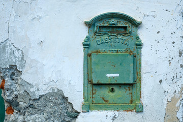 Old metal post box in a white weathered house wall in Piedmont, Italy