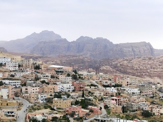 Fototapeta na wymiar Panoramic view of cityscape in Petra in Jordan, misty mountains and houses in the morning. Petra has an UNESCO World Heritage Site with a historical archaeological park.