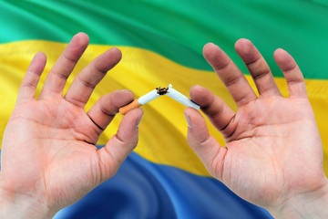 Gabon quit smoking cigarettes concept. Adult man hands breaking cigarette. National health theme...