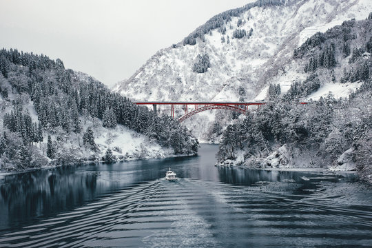 View of boat moving in lake with bridge and mountains in background