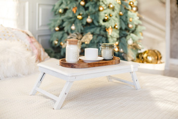 Romantic Breakfast in a bed. Romantic white bedroom decorated for New Year Celebrating. Christmas mood at home. White bedroom and Christmas spruces. 