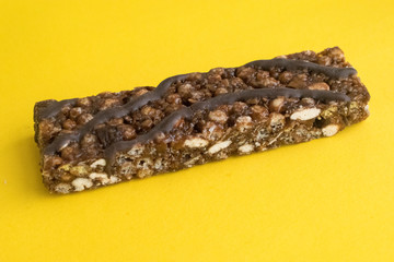 granola bar with chocolate and nuts on a yellow background