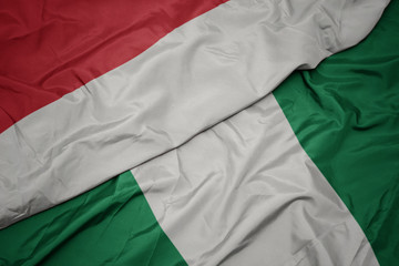 Obraz premium waving colorful flag of nigeria and national flag of indonesia.