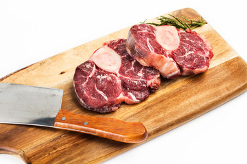 Osobuco carne cruda sobre tabla de madera rústica vista desde arriba fondo blanco