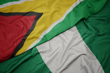 waving colorful flag of nigeria and national flag of guyana.