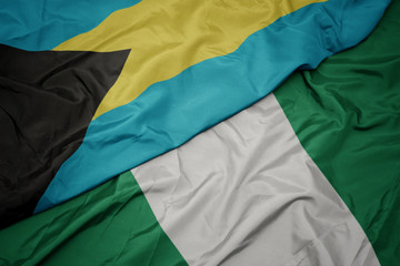 Obraz premium waving colorful flag of nigeria and national flag of bahamas.