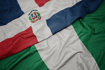waving colorful flag of nigeria and national flag of dominican republic.