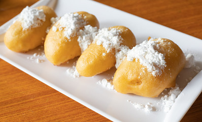 Vietnamese fried banana dough topping with Powdered sugar or icing sugar. serving on white square plate
