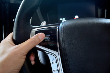 adult hand holding  the steering wheel with  multi media controler button inside of new car...