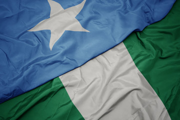 waving colorful flag of nigeria and national flag of somalia.