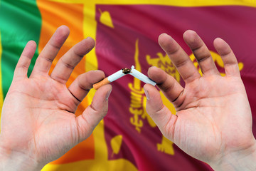 Sri Lanka quit smoking cigarettes concept. Adult man hands breaking cigarette. National health theme and country flag background.
