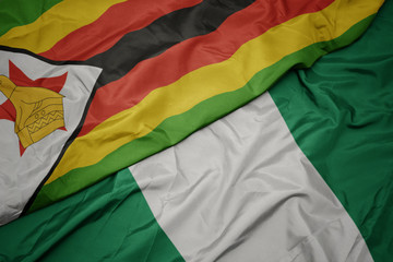 Obraz premium waving colorful flag of nigeria and national flag of zimbabwe.