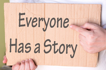 Everyone Has a Story Sign on cardboard. Man Hand Holding cardboard with text