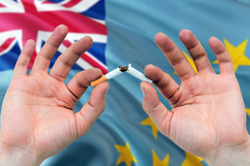 Tuvalu quit smoking cigarettes concept. Adult man hands breaking cigarette. National health theme and country flag background.