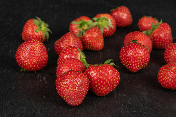 Lot of whole fresh red strawberry on grey stone