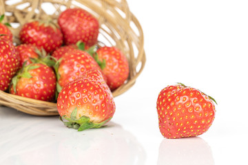 Lot of whole fresh red strawberry in round rattan bowl isolated on white background