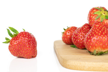 Lot of whole fresh red strawberry on bamboo cutting board isolated on white background