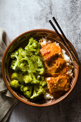 Thai salmon dish in coconut sauce with fresh broccoli and rice in a clay bowl with chopsticks . healthy food with vitamin B5...
