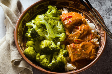 Thai salmon dish in coconut sauce with fresh broccoli and rice in a clay bowl with chopsticks . healthy food with vitamin B5...